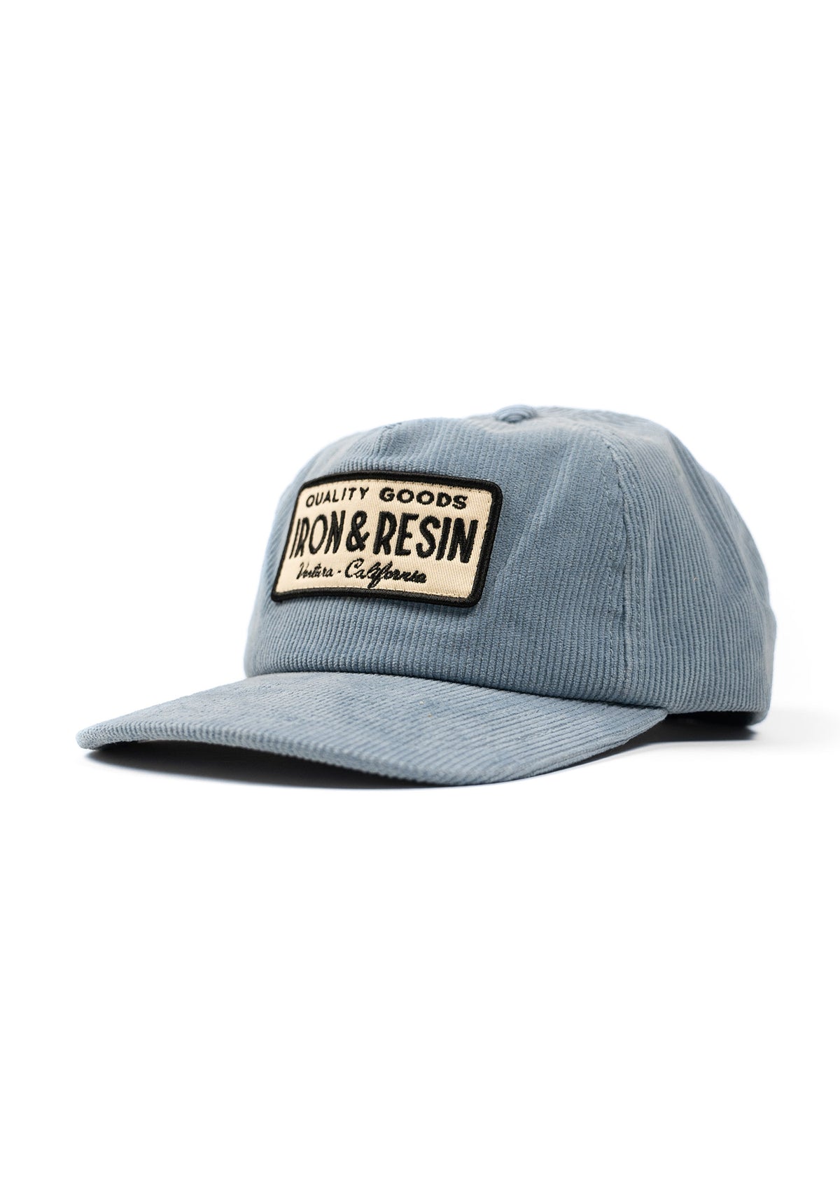 Blue corduroy cap with "Iron & Resin" patch, featuring "Quality Goods" text. Simple design, angled view on white background.