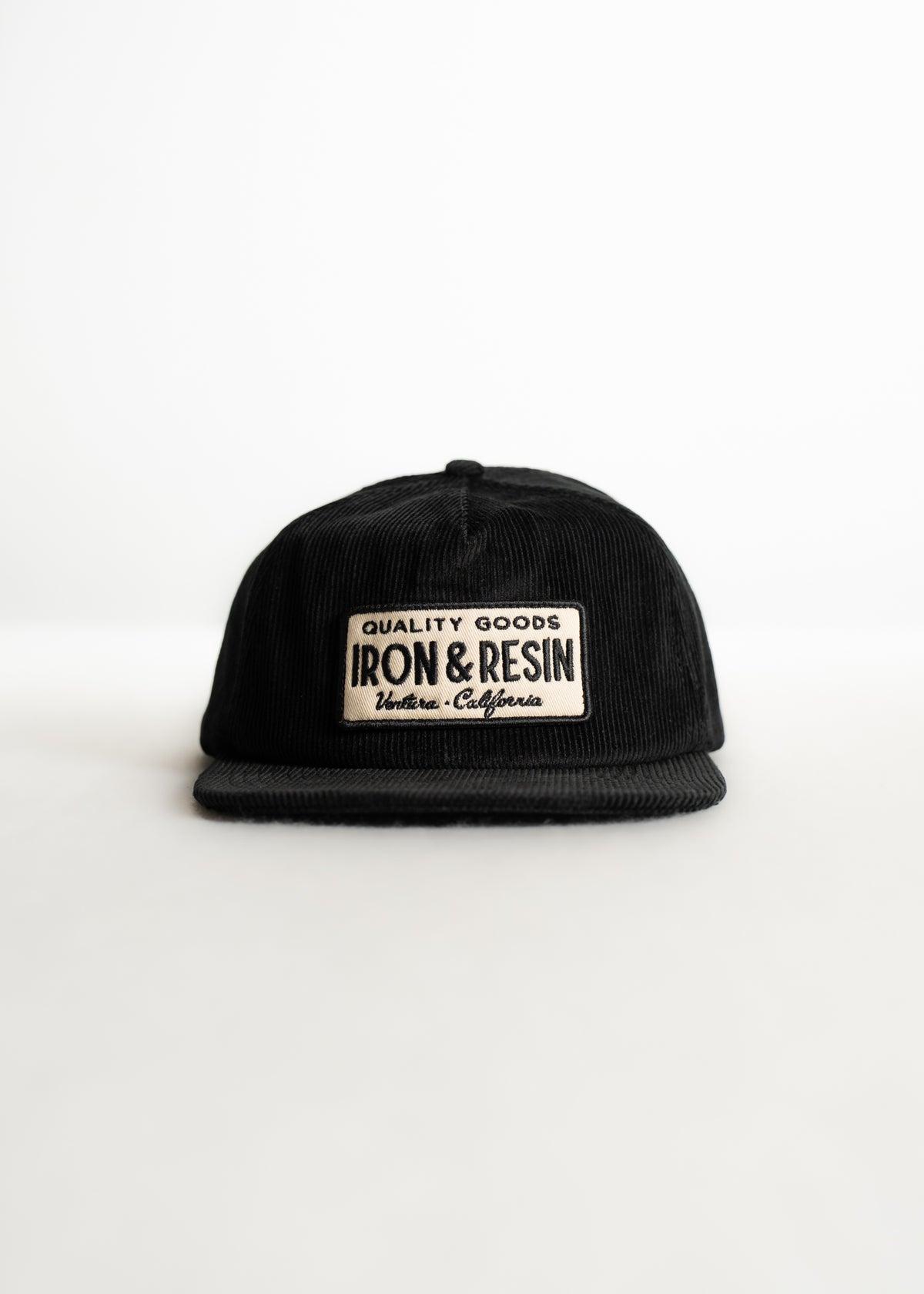 Black corduroy cap with "Quality Goods Iron & Resin Ventura, California" patch, set against a white background.