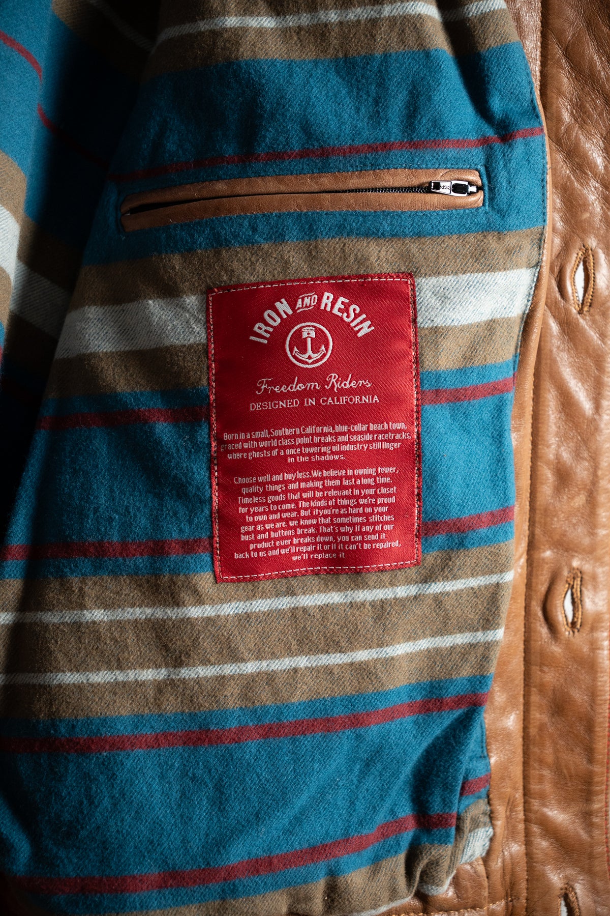 Striped fabric with a red "Iron and Resin" label and a brown zip pocket. Text highlights the brand's California design ethos.
