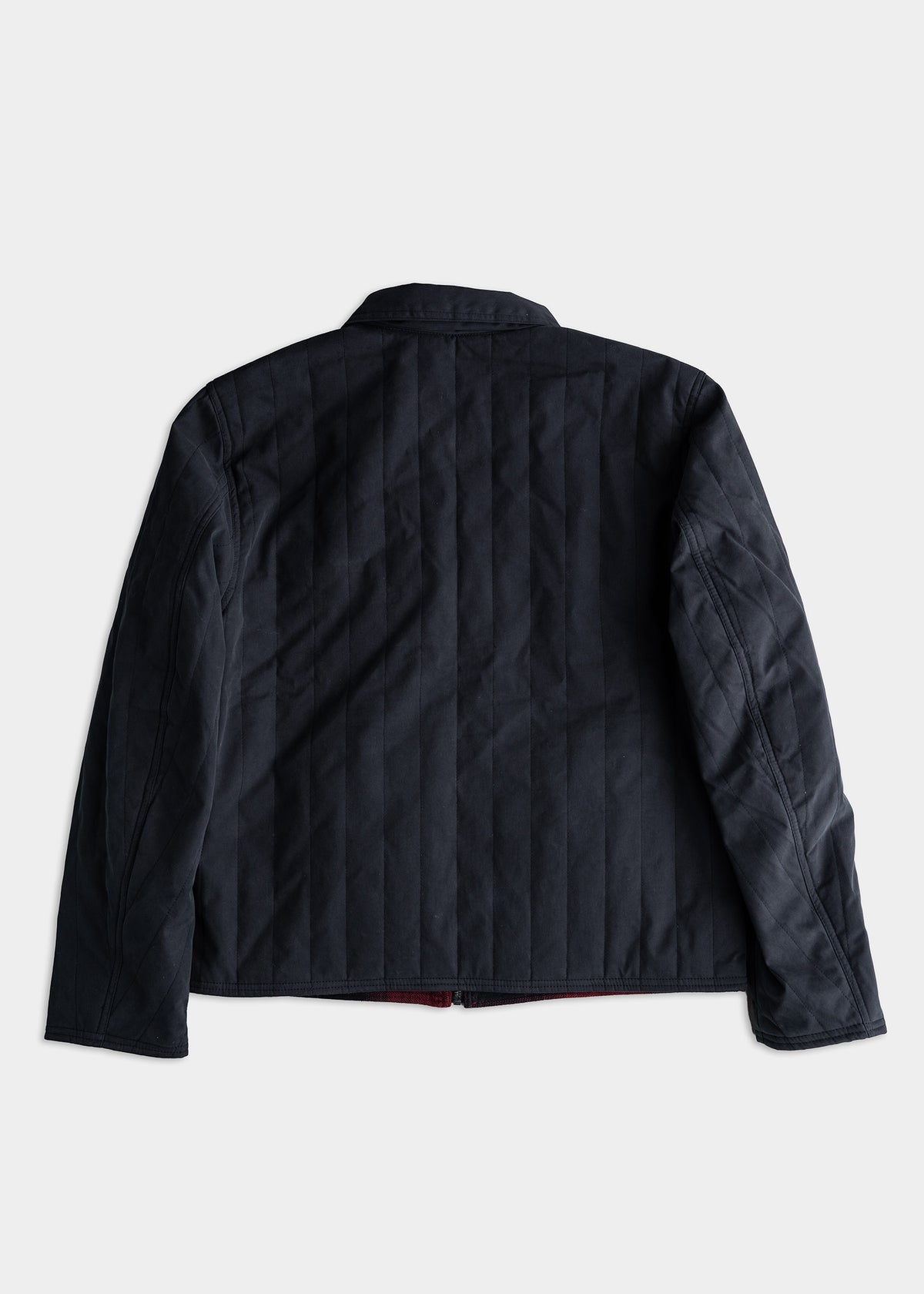 Dark quilted jacket with vertical stitching, viewed from the back against a plain background.