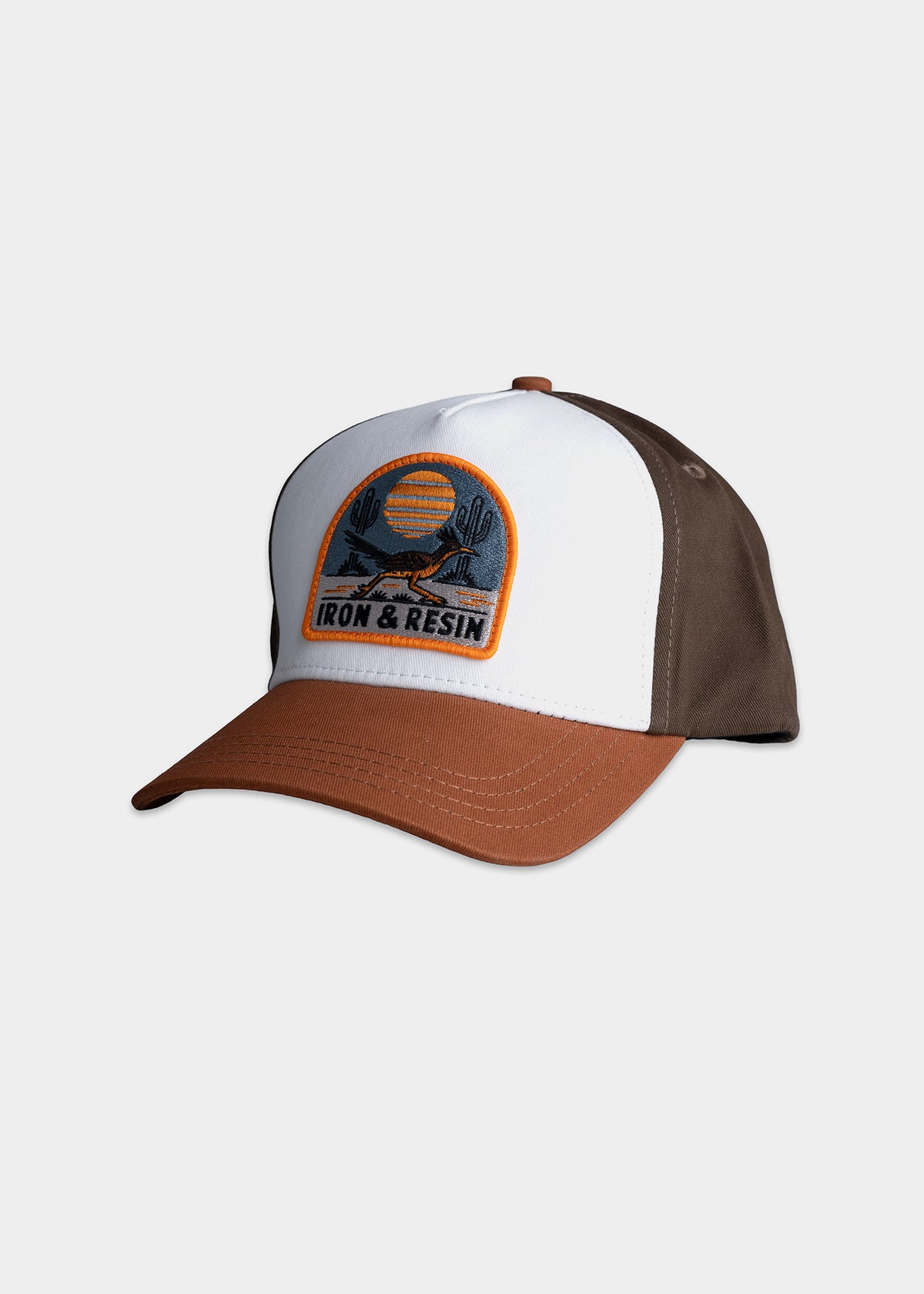 Brown and white cap with "Iron & Resin" patch featuring a desert scene with cacti and sun. Brown brim and side panels.