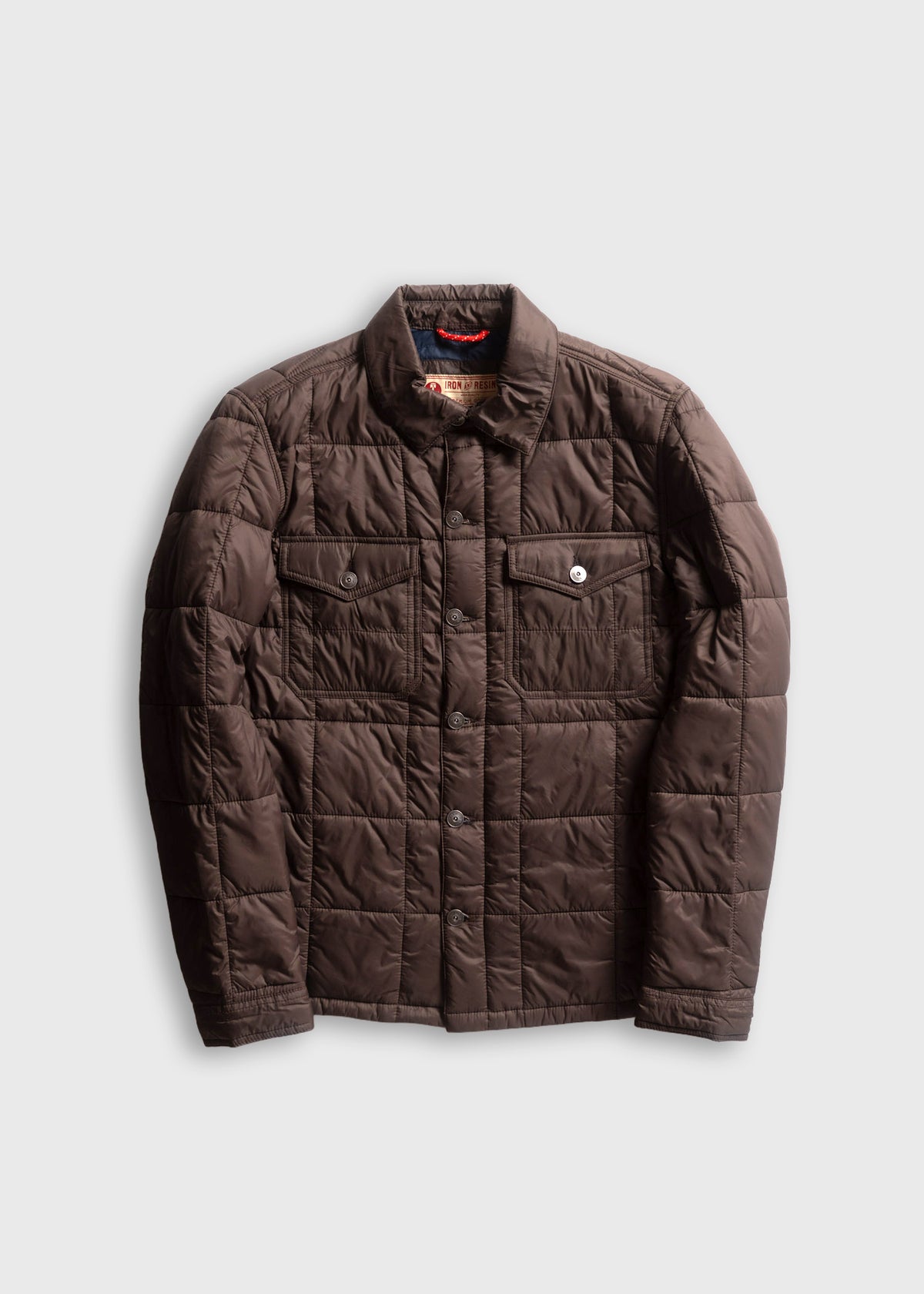 Brown quilted jacket with button closure and two chest pockets, displayed on a plain background.