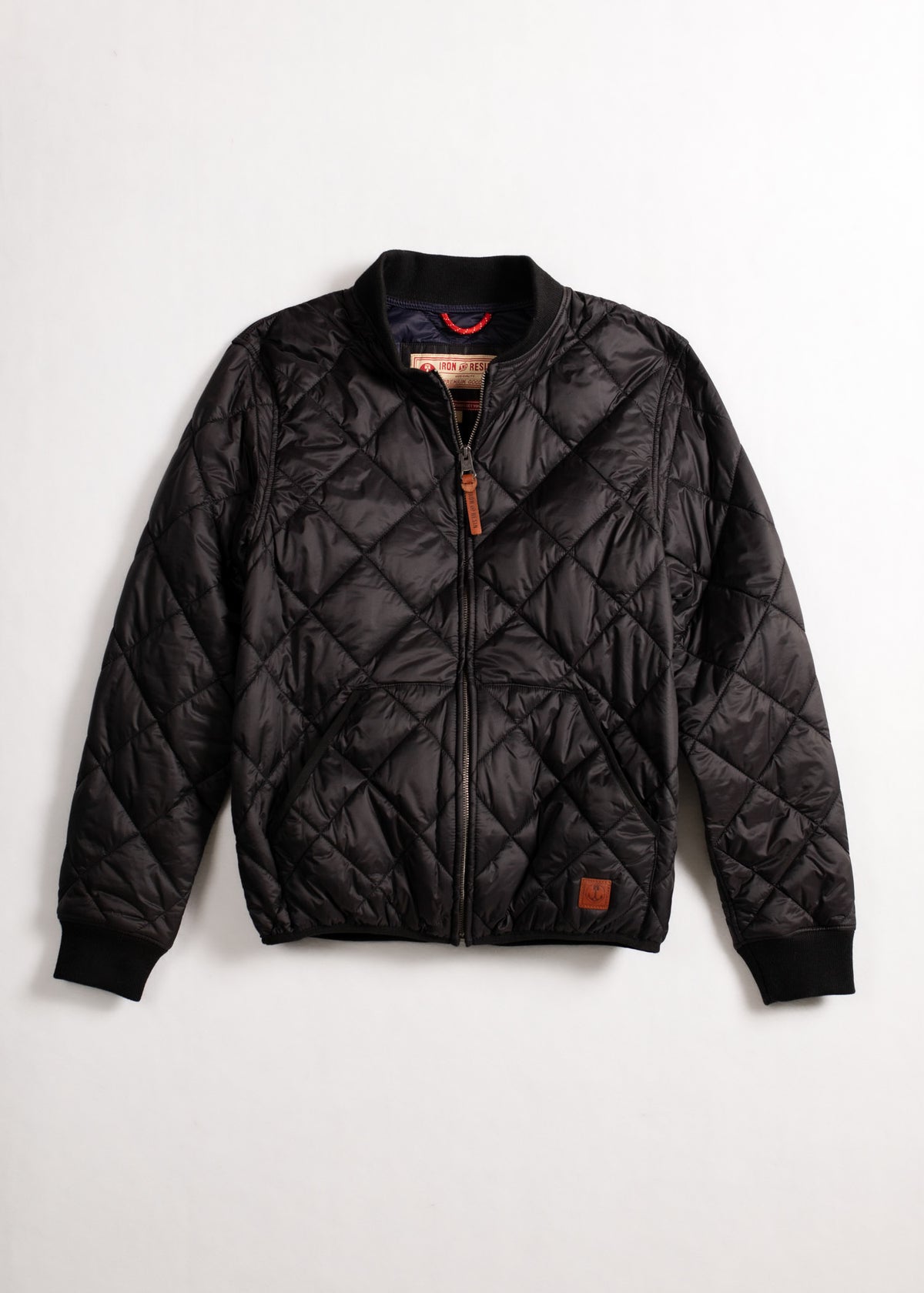 Black quilted jacket with a zipper front and ribbed cuffs, displayed on a white background. Simple, stylish outerwear choice.