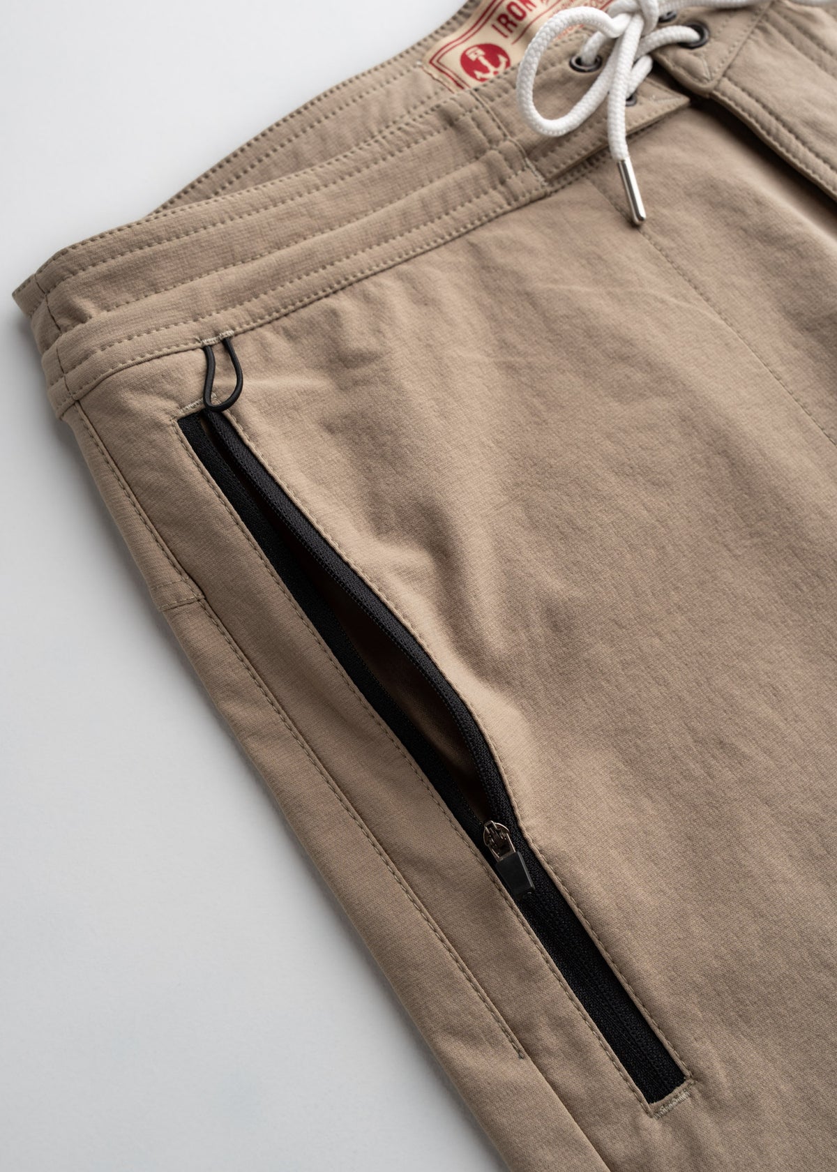 Beige shorts with a drawstring waist and a visible zipper pocket, showcasing a casual and functional design.