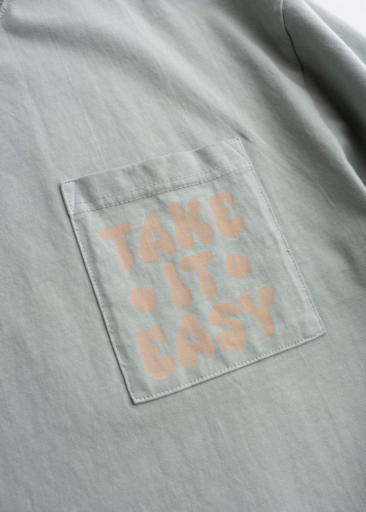 Close up of chest pocket, custom graphic print on cotton t-shirt, and highlighting print detail