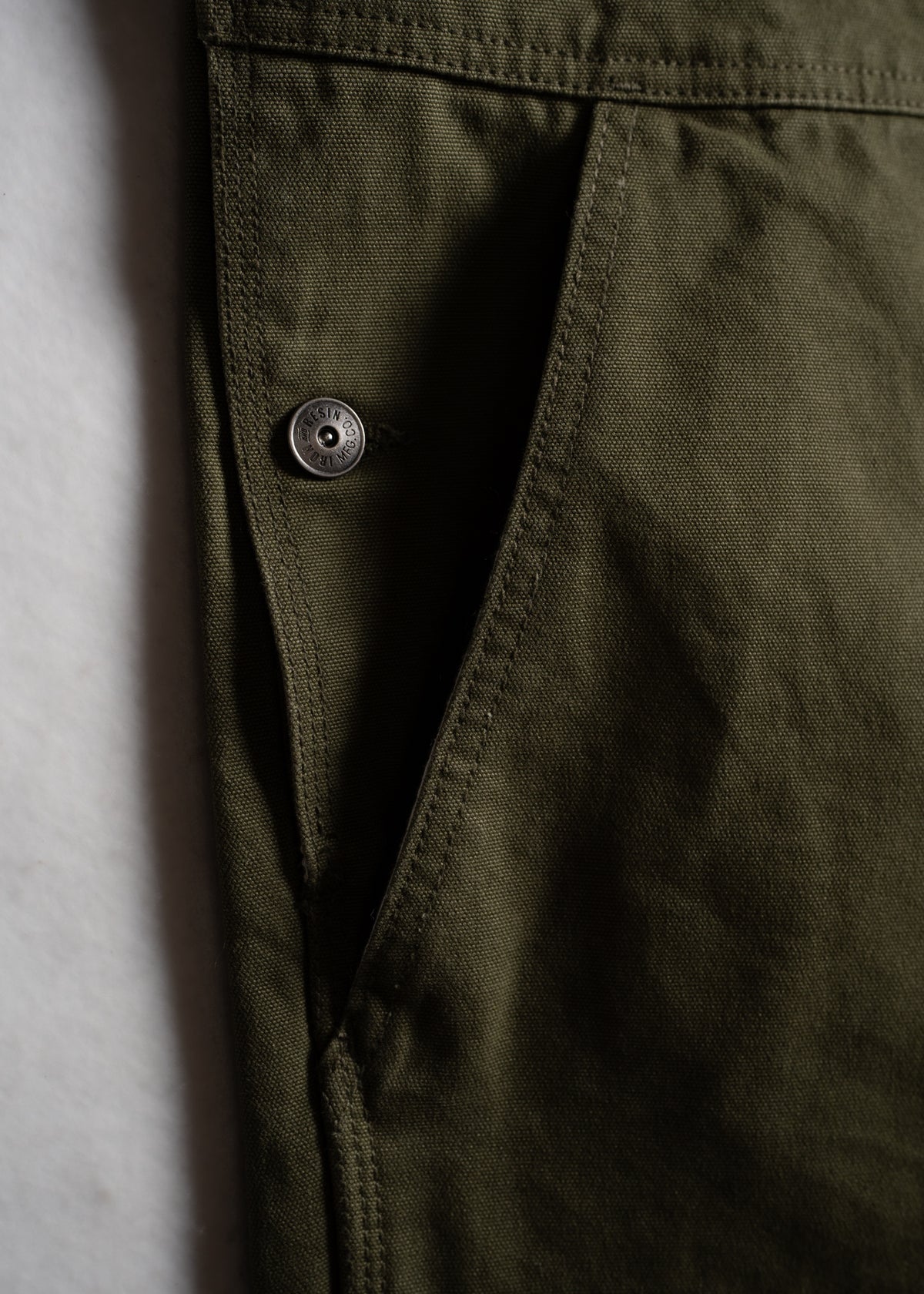 Green work overalls showcasing durable fabric, utility pockets and custom buttons.