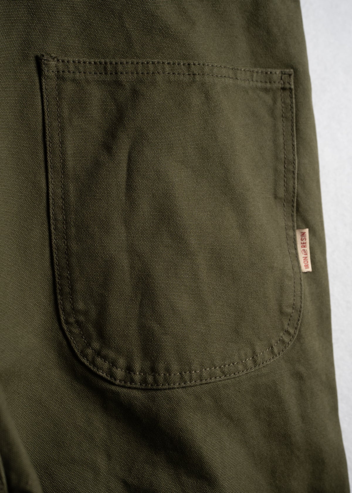Green work overalls with adjustable straps and multiple pockets, showcasing durable fabric and custom logo tag.