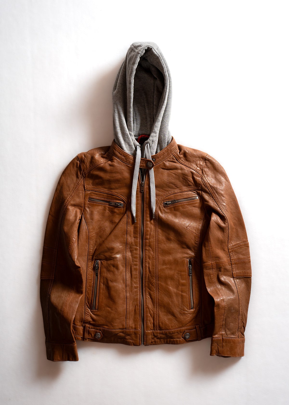 Brown leather jacket with a gray hoodie underneath, laid flat on a white background, showcasing a casual, stylish look.
