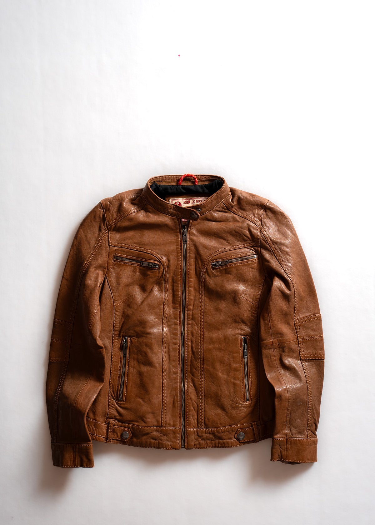Brown leather jacket with front zipper, four pockets, and a stand-up collar, laid flat on a white background.