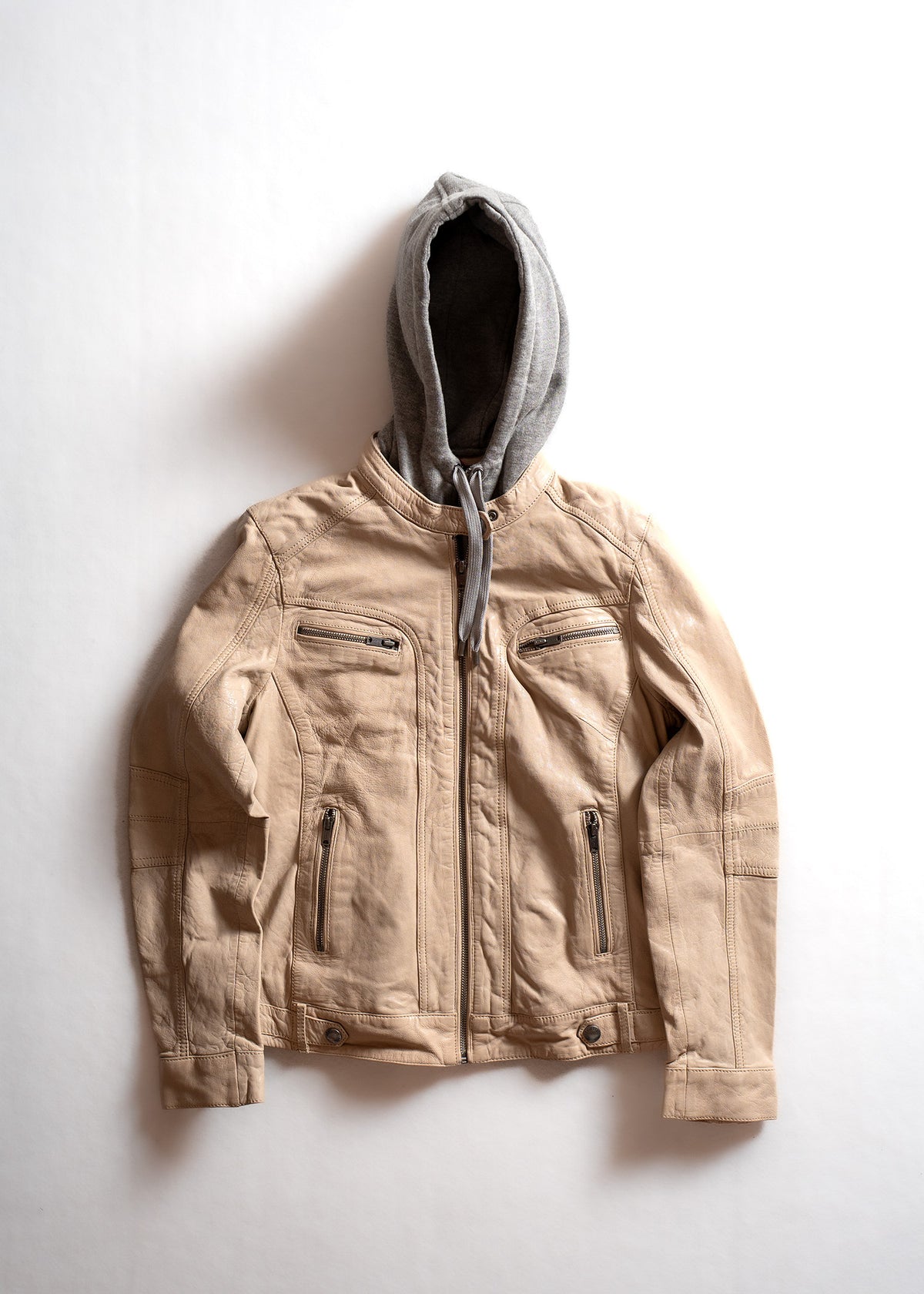 Tan leather jacket with a gray hoodie underneath, displayed on a white background, highlighting its casual, stylish design.