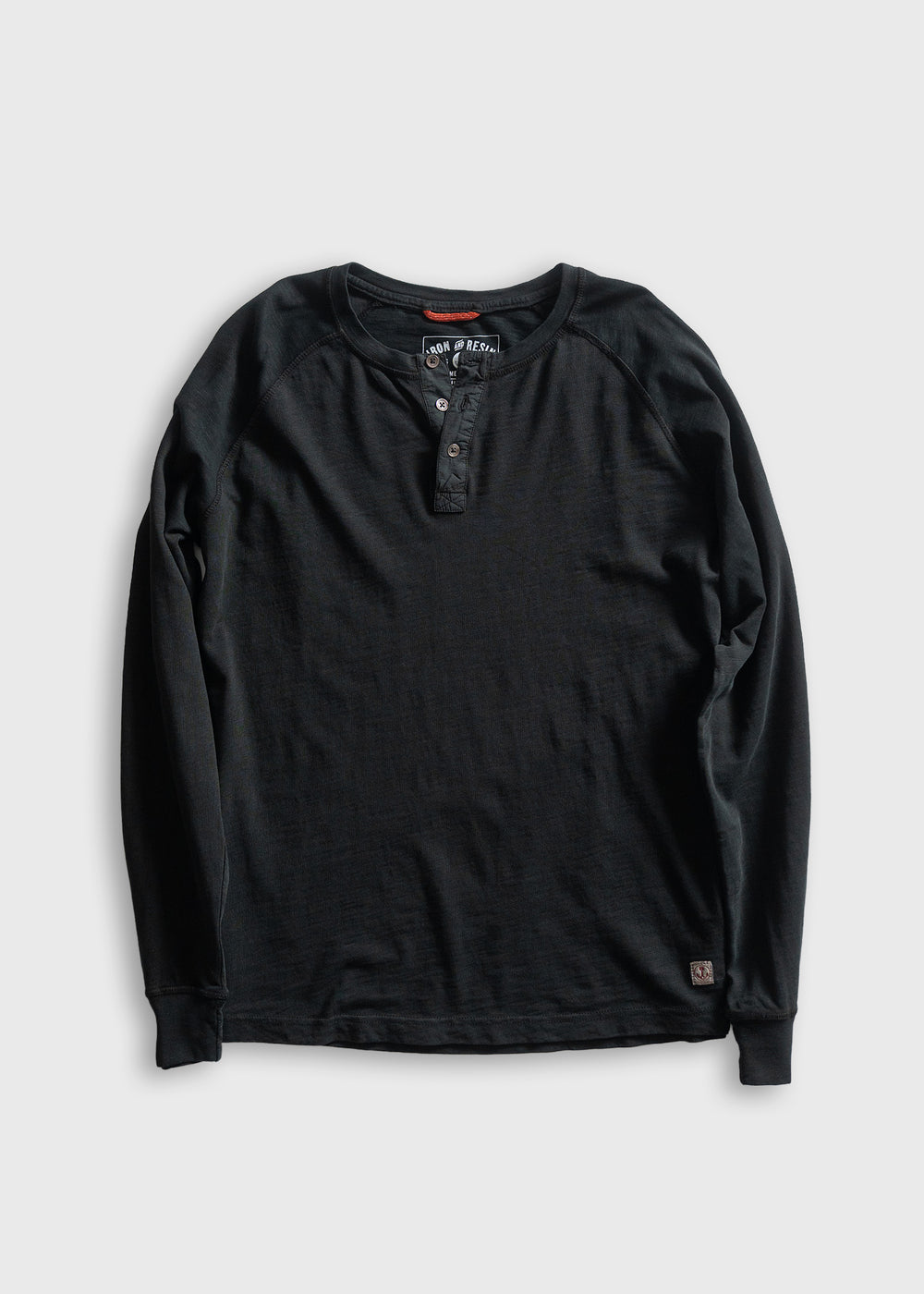 Black long-sleeve henley shirt with buttoned placket, displayed on a gray background. Simple, casual design for everyday wear.