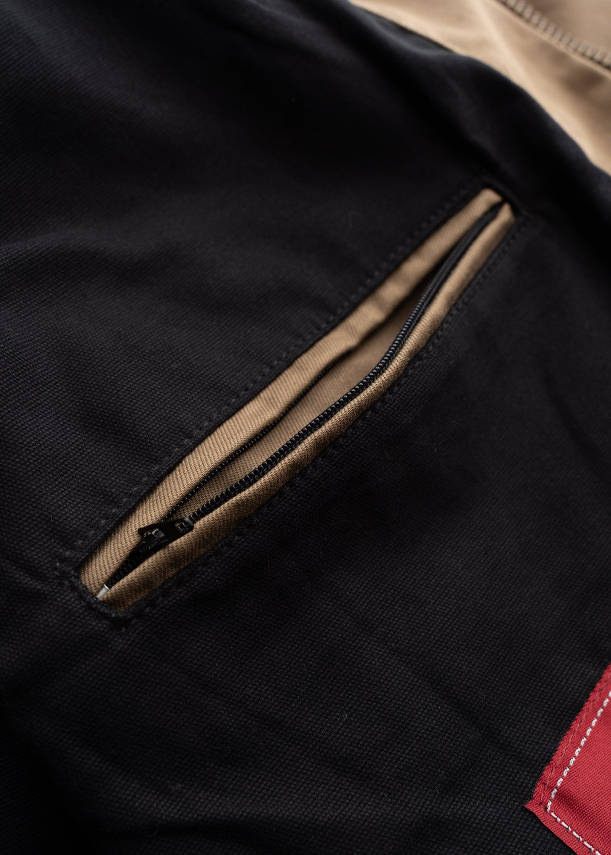 Close up of inner jacket pocket, showcasing zippered top entry design and utility storage