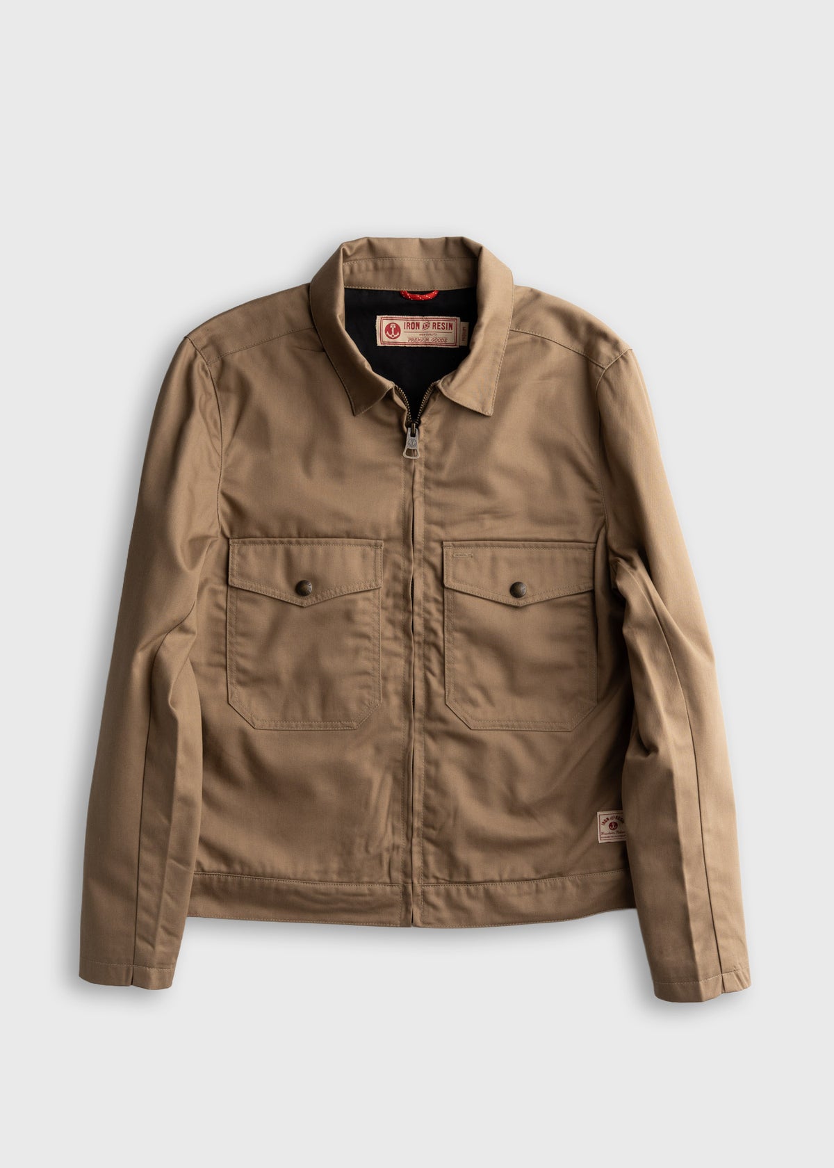 Tan canvas jacket with a collar, front zipper, and two chest pockets, displayed on a white background.
