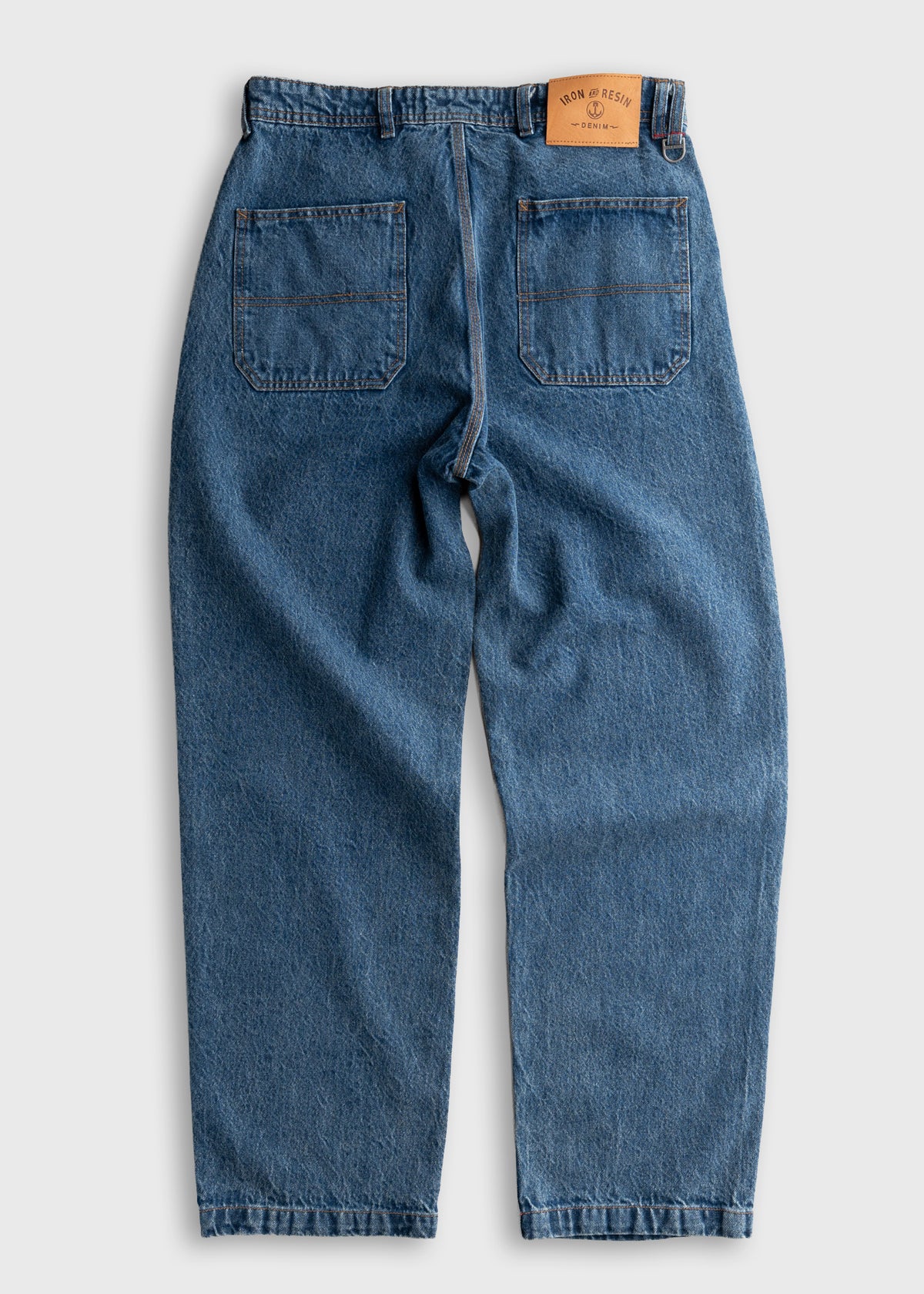 Blue denim jeans with two back pockets and a brown leather patch on the waistband, displayed on a light background.