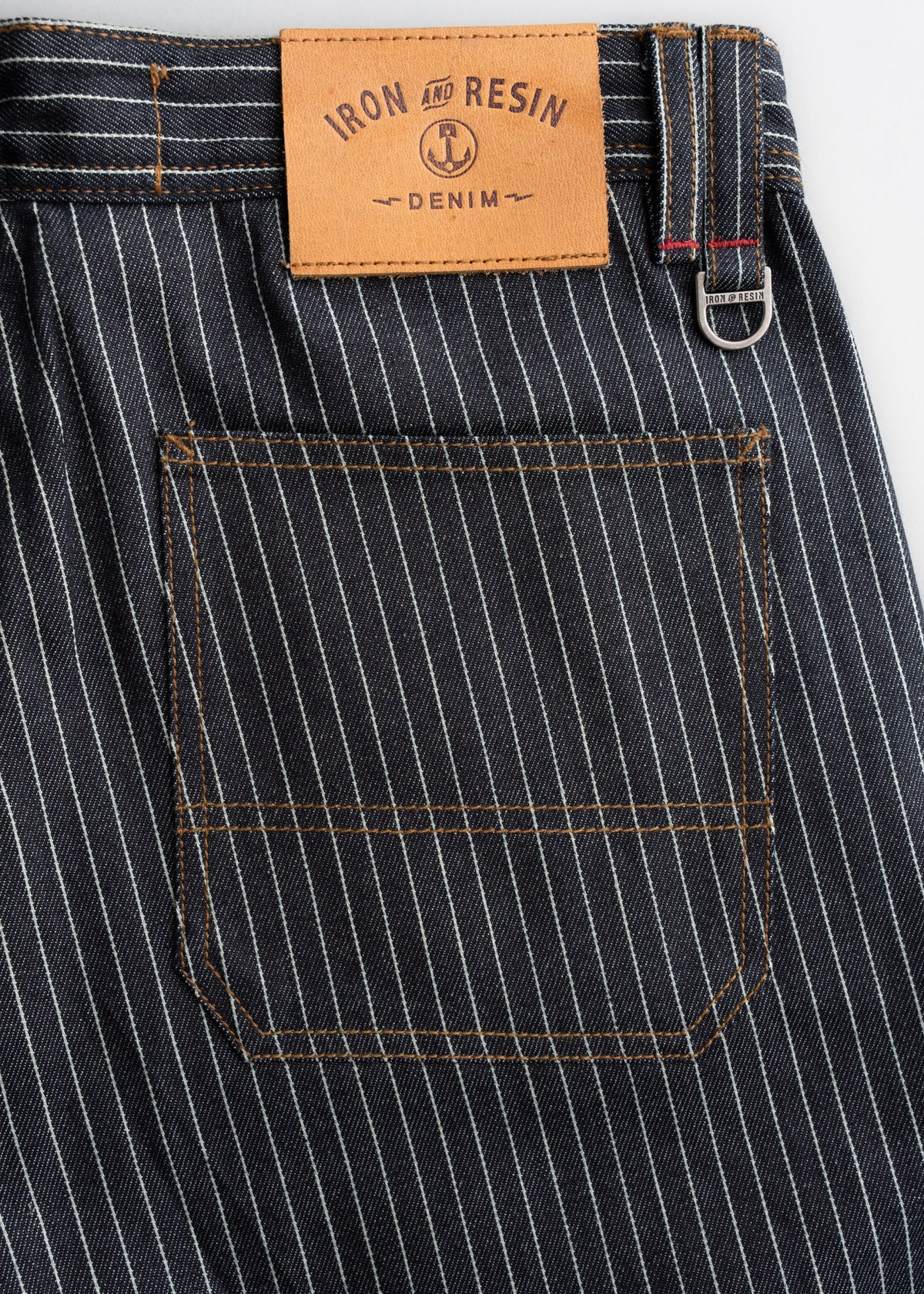 Striped denim with a brown "Iron and Resin" label above the back pocket, showcasing detailed stitching and a metal loop.