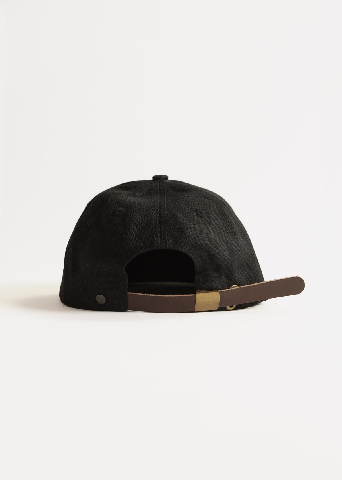 Black cap with brown adjustable strap on a white background, showcasing its back view and simple design.
