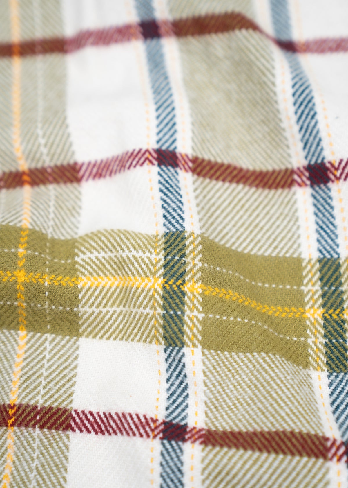 Close-up of a plaid fabric with green, red, and blue stripes on a white background, showcasing a classic checkered pattern.