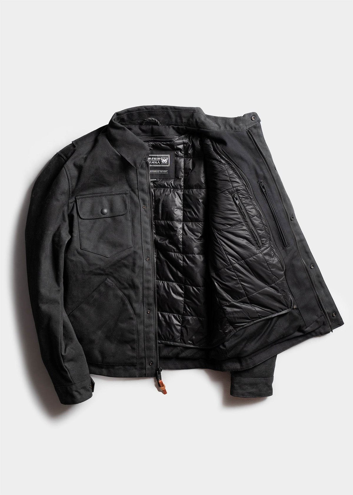 Black jacket with quilted lining, open to reveal interior pockets. Features buttoned chest pocket and sleek design.