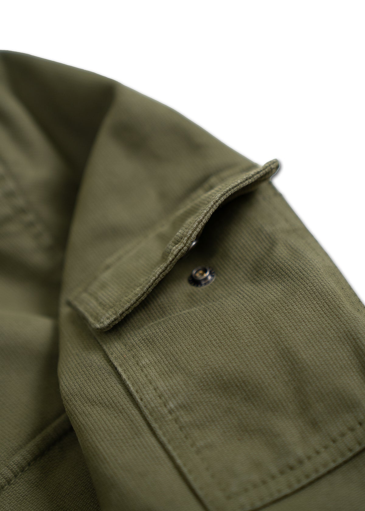 Close-up of an olive green fabric with a metal snap button and a flap, showcasing texture and stitching details.