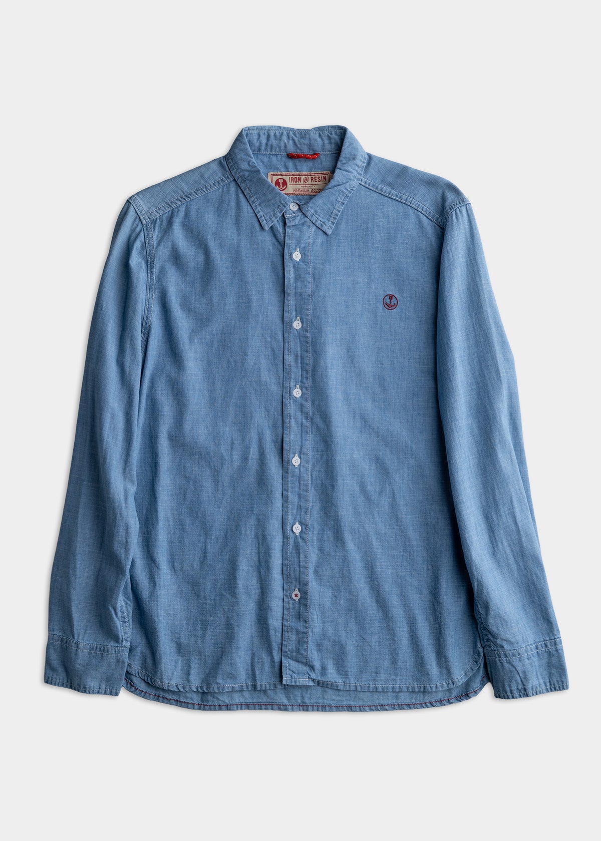 Blue denim shirt with button-down collar and embroidered logo, displayed on a white background. Casual and stylish design.