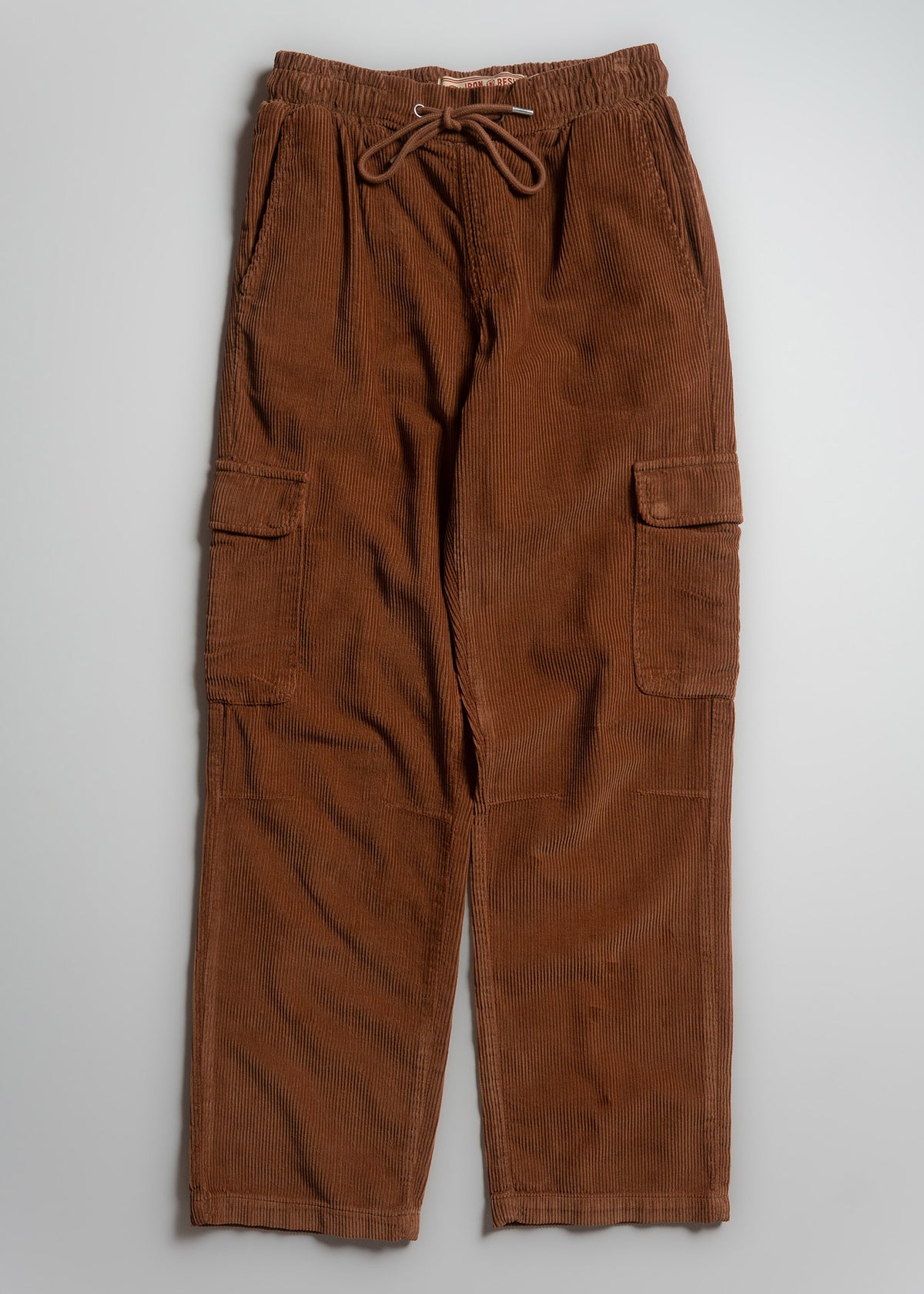 Brown corduroy cargo pants with drawstring waist and side pockets, laid flat on a light gray background.